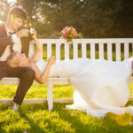 After-Wedding-Shooting bei tiefstehender Abendsonne im Schwetzinger Schlossgarten auf einer Parkbank mit coolem Paar und Bierflaschen
